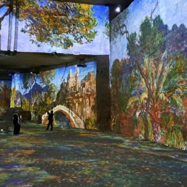 Visitors surrounded by giant impressionist paintings projected onto the stone walls of Carrières des Lumières
