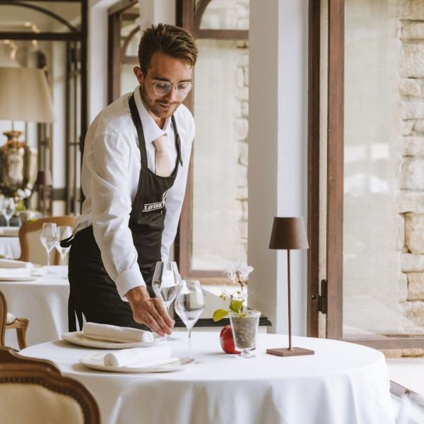 Waiter setting a white-linen table in an elegant fine-dining restaurant in Provence